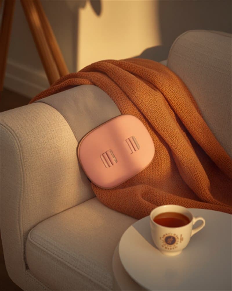 The Ember belt on the sofa with a throw blanket and tea
